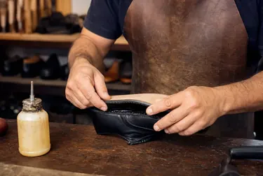 Sapateiro em Vitória utilizando cola para fixar a sola de um calçado.